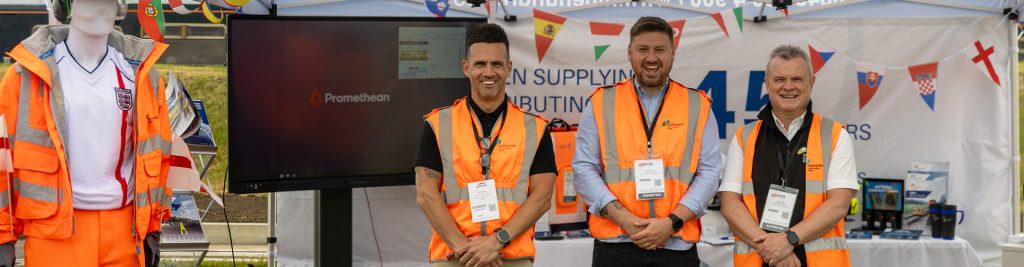 Three men wearing orange vests at Rail Live