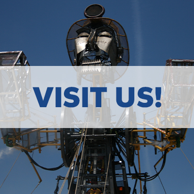 visit us logo in front of a giant robot statue