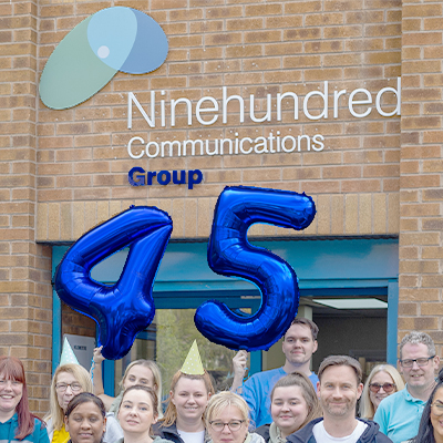 the ninehundred communications group infront of their building holding their 45 years celebration balloon