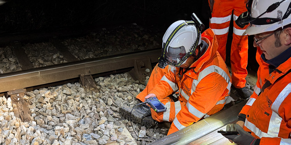 Workers inspecting railway track at night.