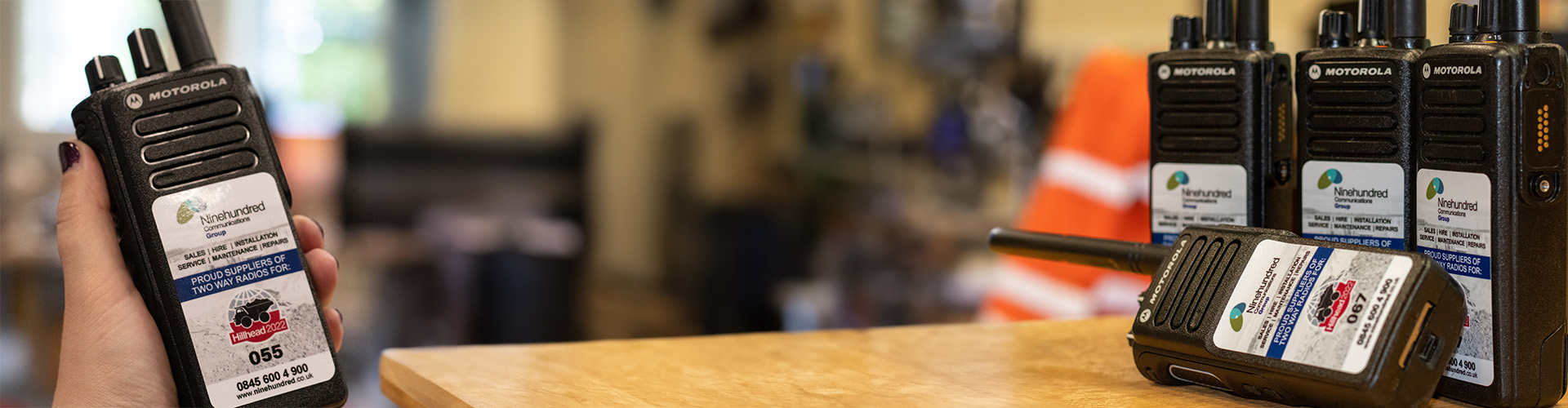 two way radios on a table in the office with a womens hand holding a two way radio