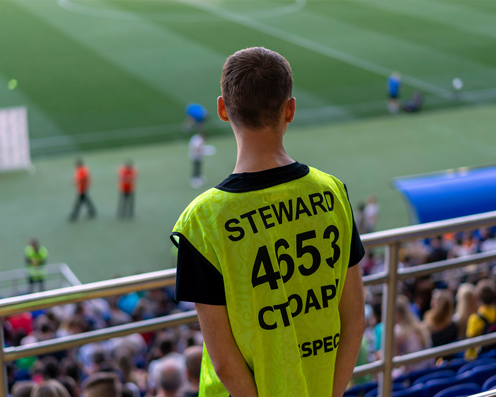 a man in a yellow shirt with a football field in the background
