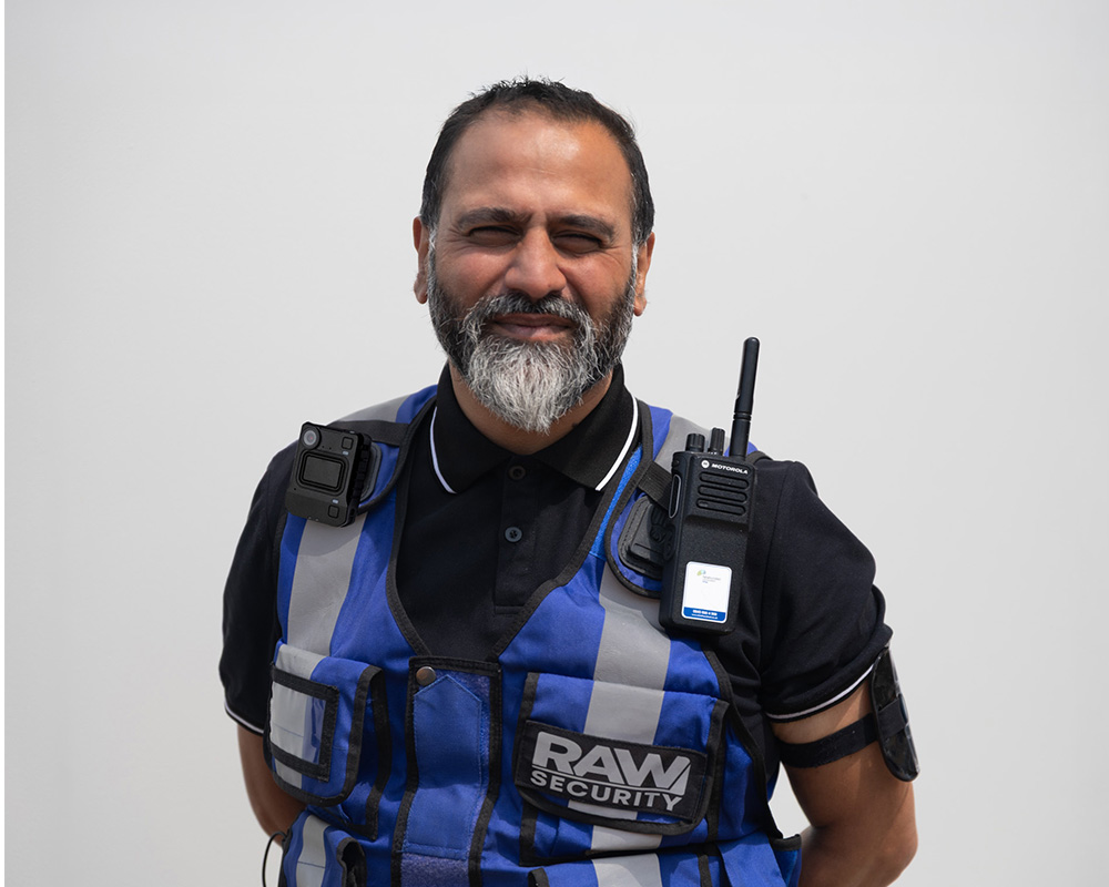 Smiling security guard in uniform with body camera and radio