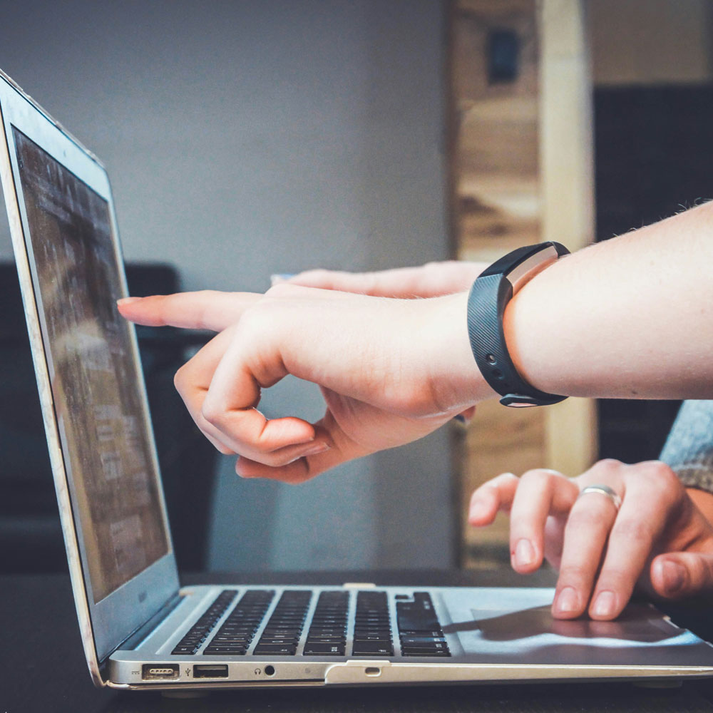 two hands pointing at a computer screen